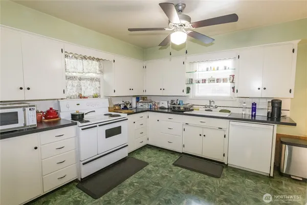 a kitchen with granite countertop white cabinets white stainless steel appliances with a sink and a window
