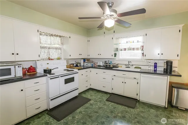 a kitchen with granite countertop white cabinets white stainless steel appliances with a sink and a window