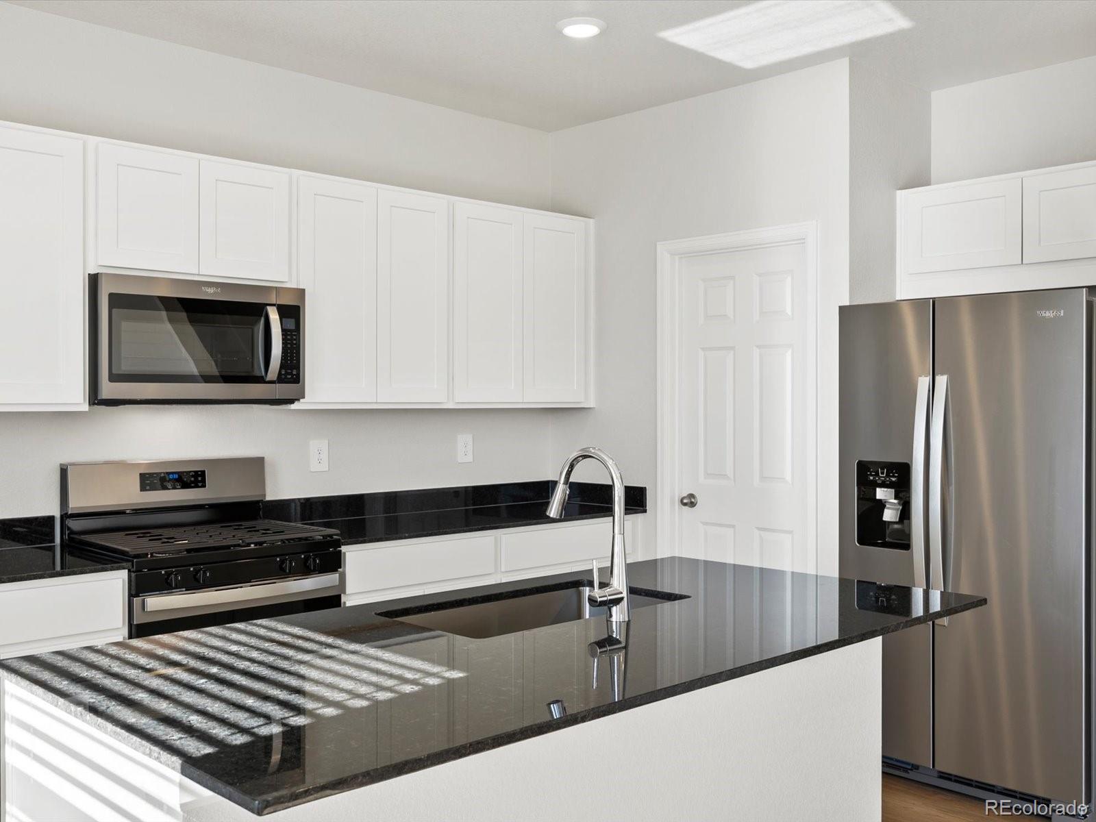 7335 West 27th Street Greeley, CO 80634 - Photo 6 of 25 a kitchen with stainless steel appliances granite countertop a refrigerator a stove and a sink