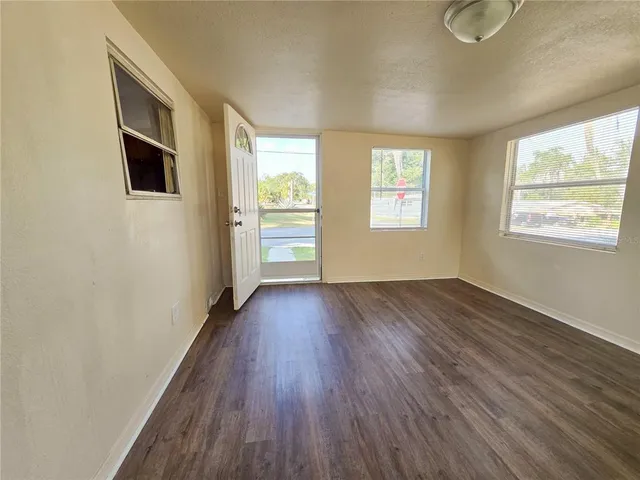 a view of an empty room with wooden floor and a window