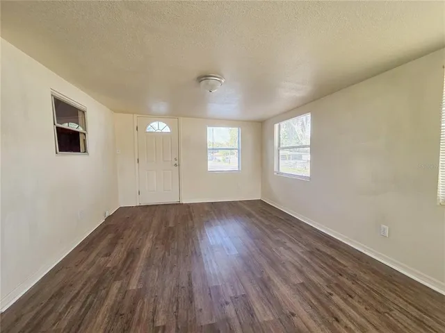 a view of an empty room with wooden floor and window