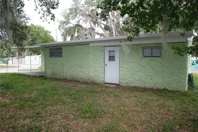 a view of a house with a yard and a large tree