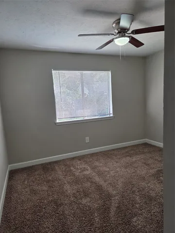 an empty room with a chandelier fan and windows