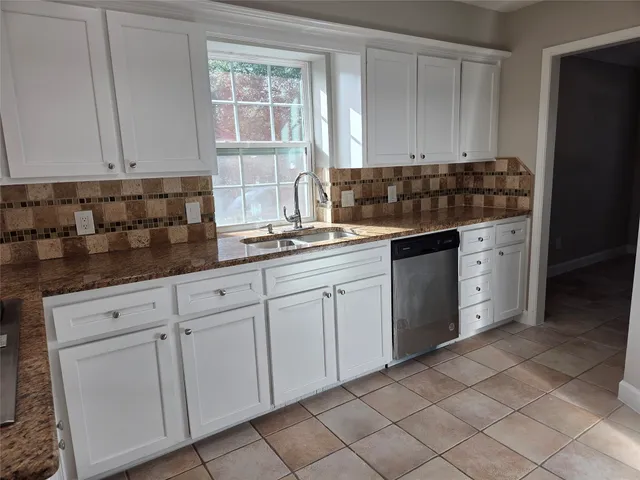 a kitchen with white cabinets and sink