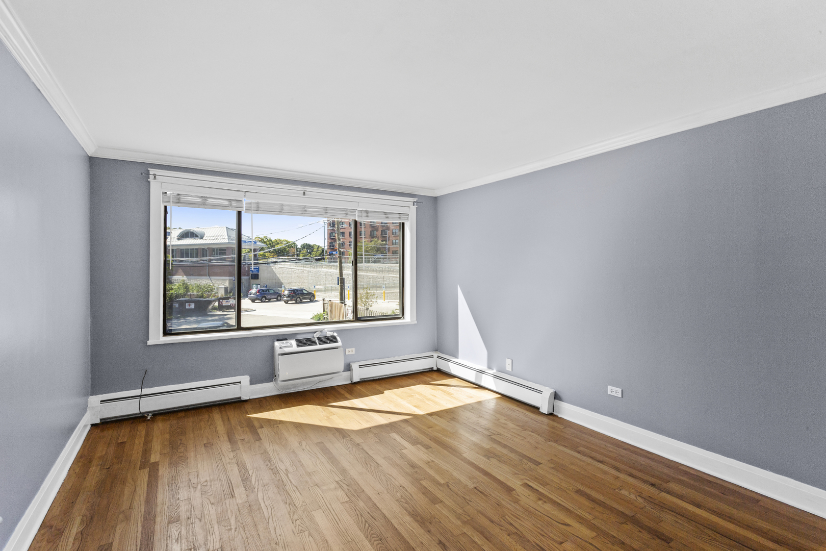 6060 North Ridge Avenue, Unit 2H Chicago, IL 60660 - Photo 3 of 23 an empty room with wooden floor and a window
