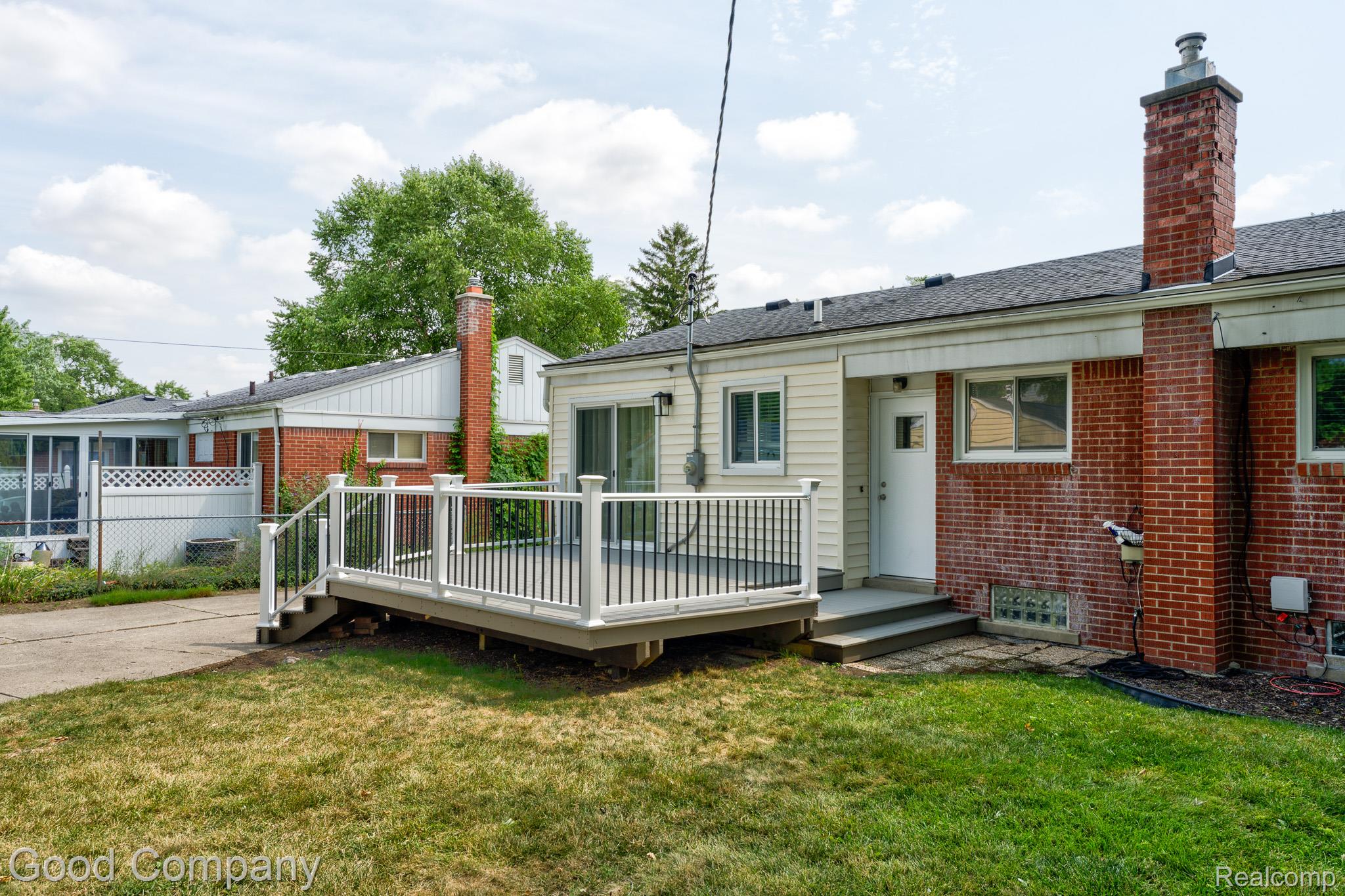 1842 Massoit Road Royal Oak, MI 48073 - Photo 46 of 52 Outdoor deck with white railing, sliding glass door, brick and siding exterior, and a manicured lawn