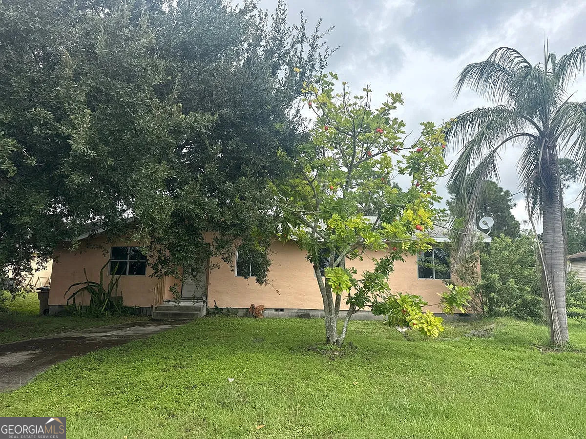 4106 3rd Street Southwest Lehigh Acres, FL 33976 - Photo 2 of 5 a backyard of a house with table and chairs plants and large tree