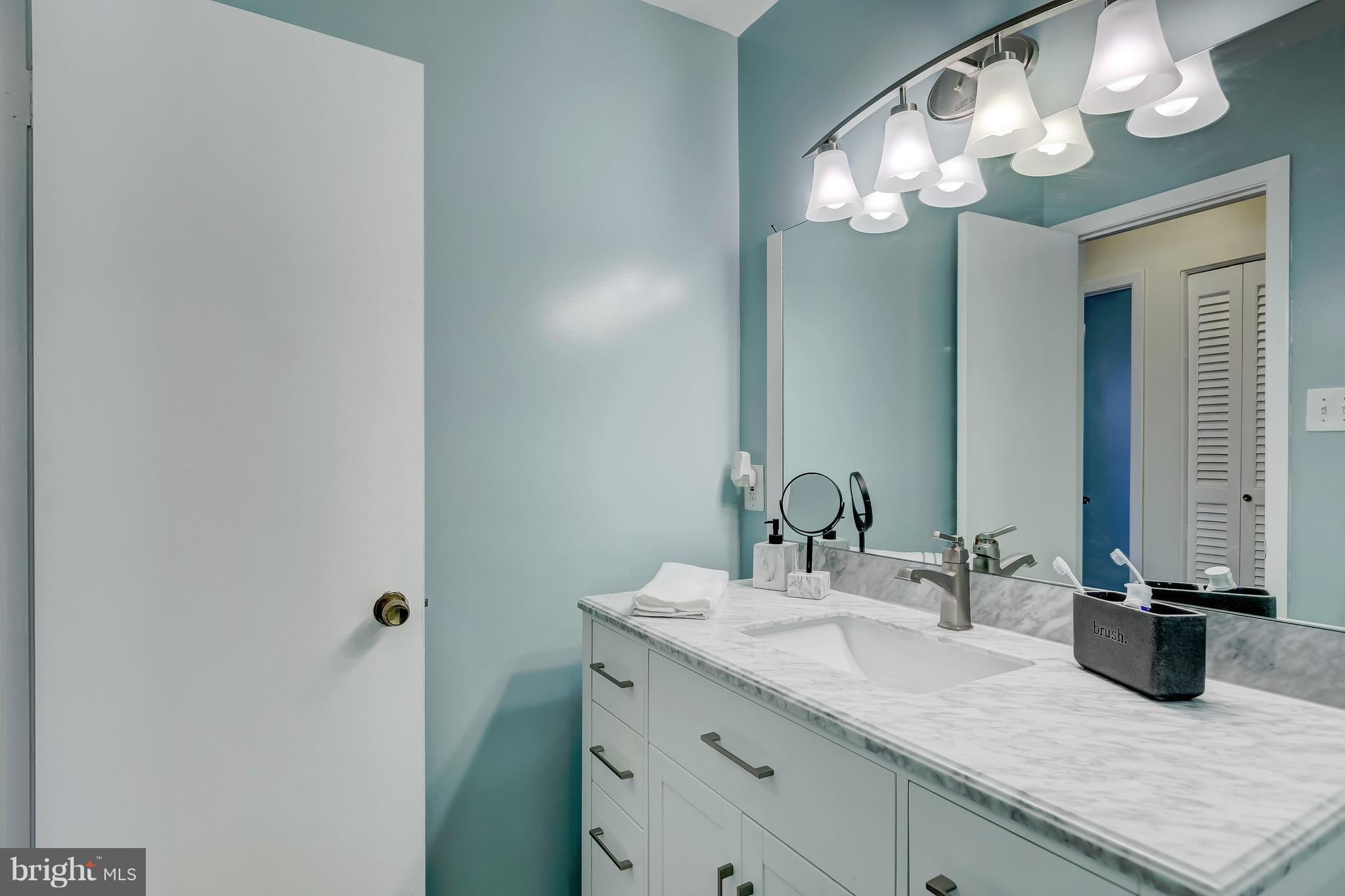 8004 Arrowhead Road Baltimore, MD 21208 - Photo 22 of 30 a bathroom with a granite countertop sink a large mirror and vanity