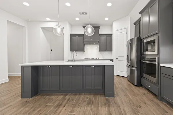 a open kitchen with stainless steel appliances granite countertop a sink dishwasher a stove and a refrigerator with wooden floor