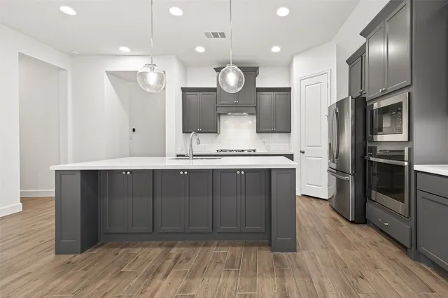 a open kitchen with stainless steel appliances granite countertop a sink dishwasher a stove and a refrigerator with wooden floor