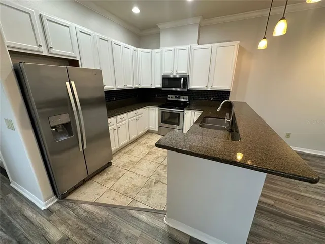 a kitchen with stainless steel appliances granite countertop a sink a stove and a refrigerator