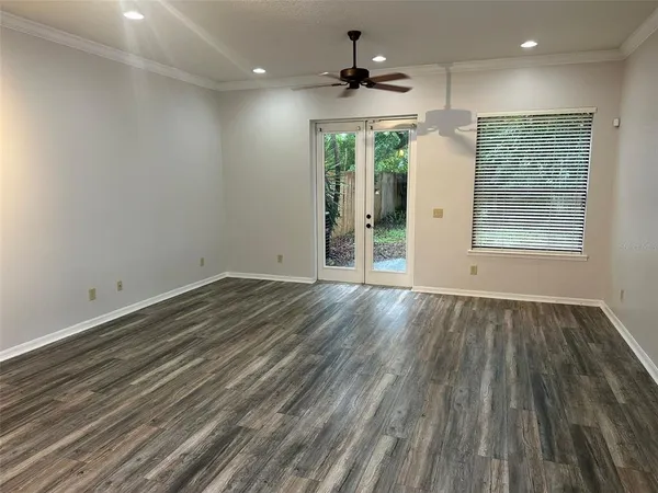 an empty room with wooden floor and a ceiling fan