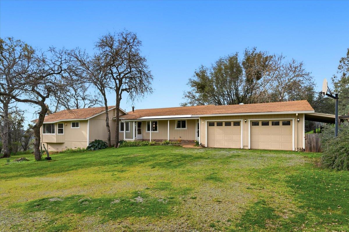 a view of a house next to a big yard and large trees