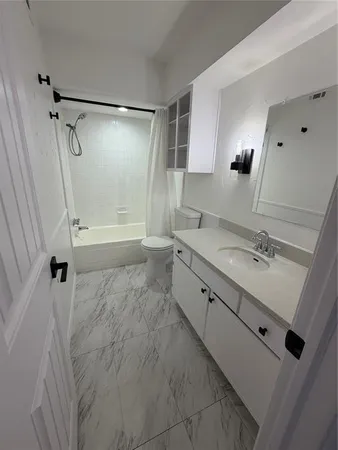 a bathroom with a granite countertop sink a mirror a bathtub and shower