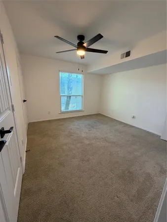 an empty room with a ceiling fan and window