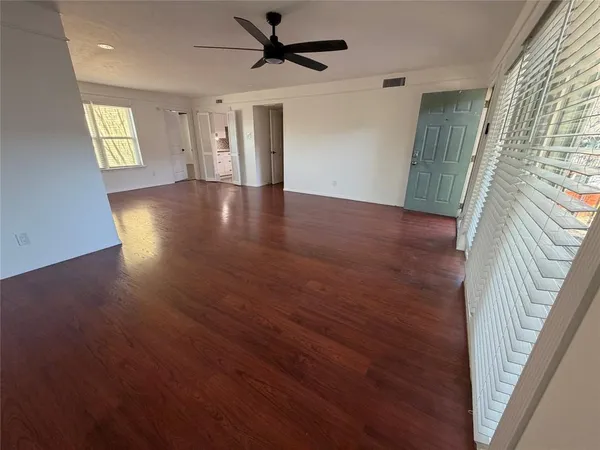 an empty room with wooden floor and windows