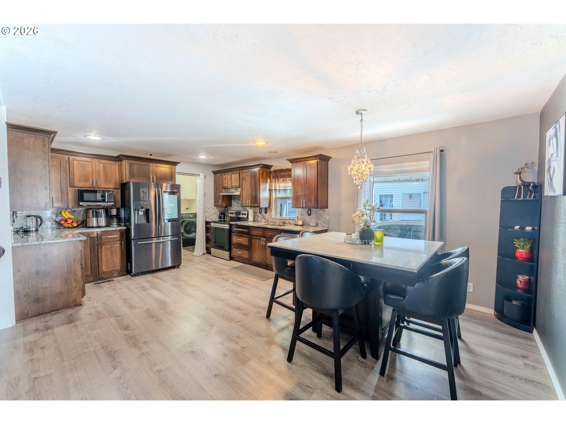 4364 Bren Loop Northeast, Unit 95 Salem, OR 97305 - Photo 12 of 34 a kitchen with stainless steel appliances kitchen island granite countertop a table chairs and a refrigerator