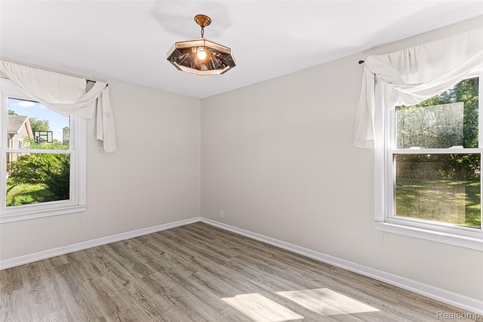 2550 Loon Lake Road Wixom, MI 48393 - Photo 23 of 36 Light gray wall paint, wood-finish flooring, two windows, and an overhead light fixture