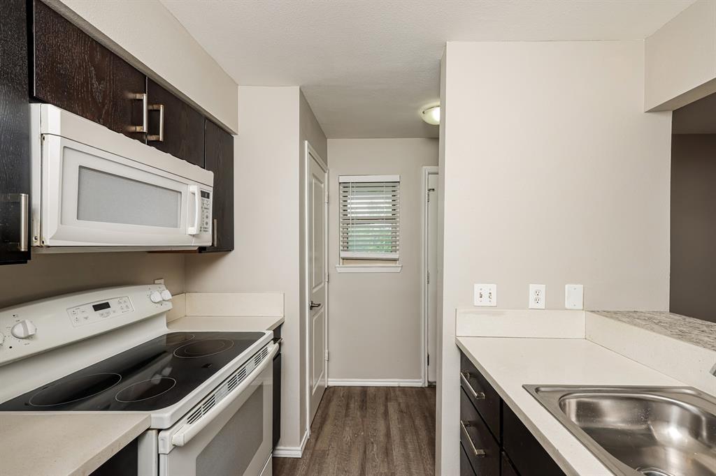 4622 Monarch Street, Unit 202 Dallas, TX 75204 - Photo 9 of 16 Galley kitchen featuring dark wood-finish cabinetry with silver hardware, light-toned countertops, and a stainless steel sink
