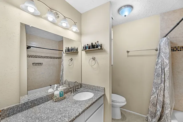 a bathroom with a granite countertop sink toilet and shower