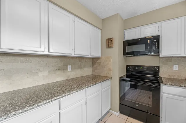 a kitchen with granite countertop white cabinets and black appliances