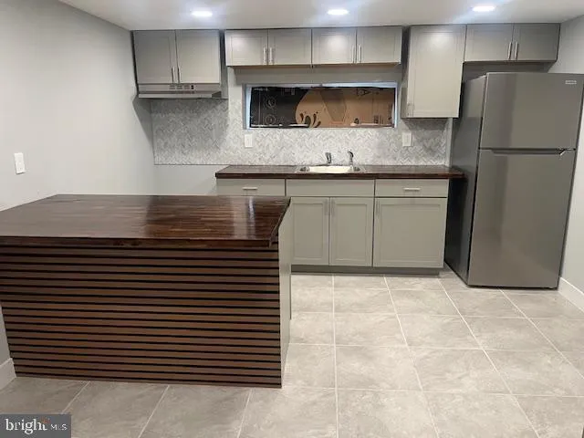 a kitchen with a sink a refrigerator and cabinets