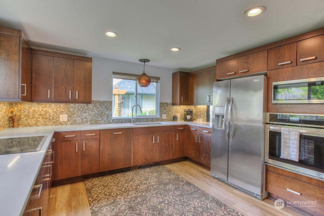 32911 4th Lane South Federal Way, WA 98003 - Photo 5 of 19 a kitchen with stainless steel appliances granite countertop a refrigerator a stove and a sink with wooden cabinets