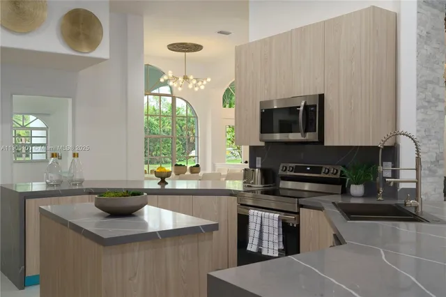 a kitchen with stainless steel appliances a stove a sink a microwave a refrigerator and cabinets