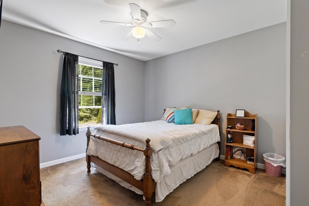 297 Manchaug Road Sutton, MA 01590 - Photo 17 of 40 a bedroom with a bed and a chandelier