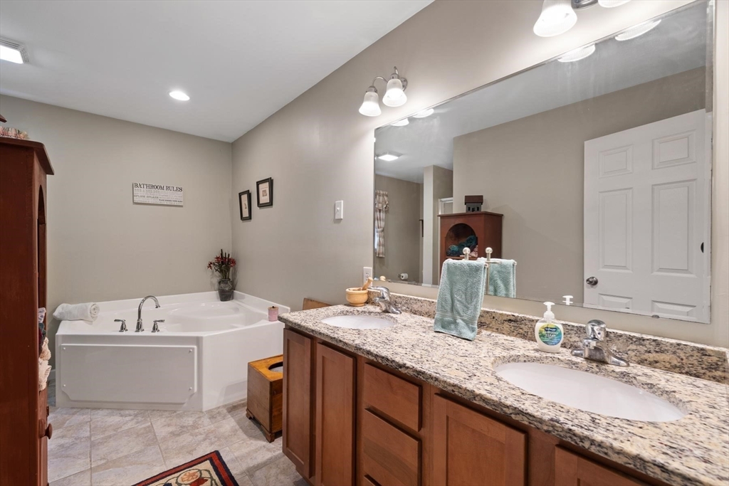 297 Manchaug Road Sutton, MA 01590 - Photo 8 of 40 a bathroom with a granite countertop sink a large mirror and a bathtub
