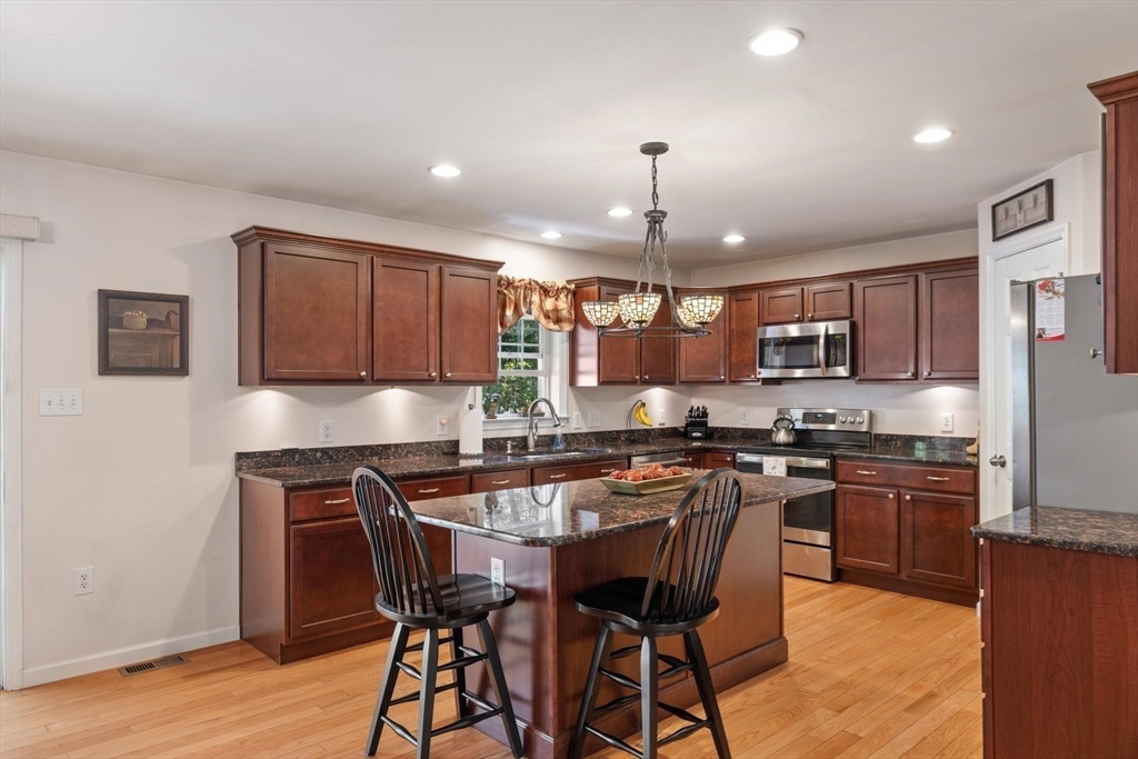 297 Manchaug Road Sutton, MA 01590 - Photo 9 of 40 a kitchen with stainless steel appliances a table chairs sink and stove top oven