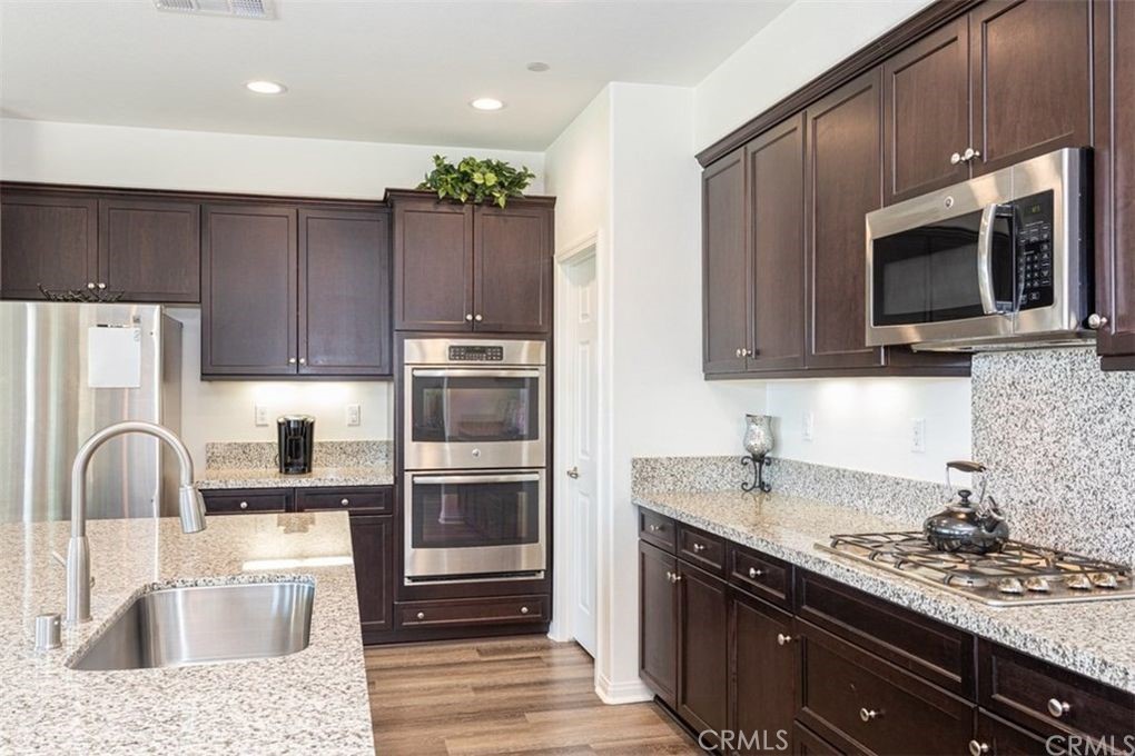 24125 Montecito Drive Wildomar, CA 92595 - Photo 3 of 25 a kitchen with kitchen island granite countertop a sink stove and refrigerator