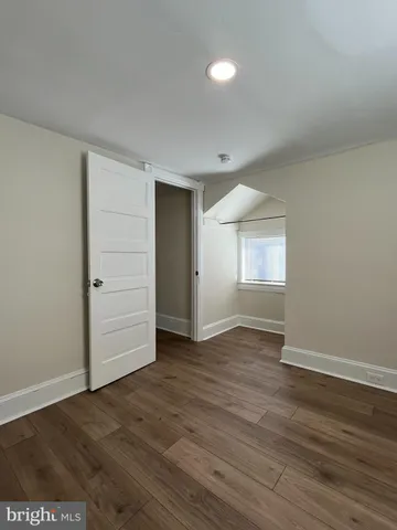 an empty room with wooden floor & cabinet and windows