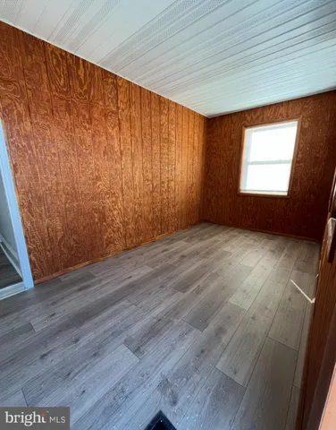 an empty room with wooden floor and windows with curtains