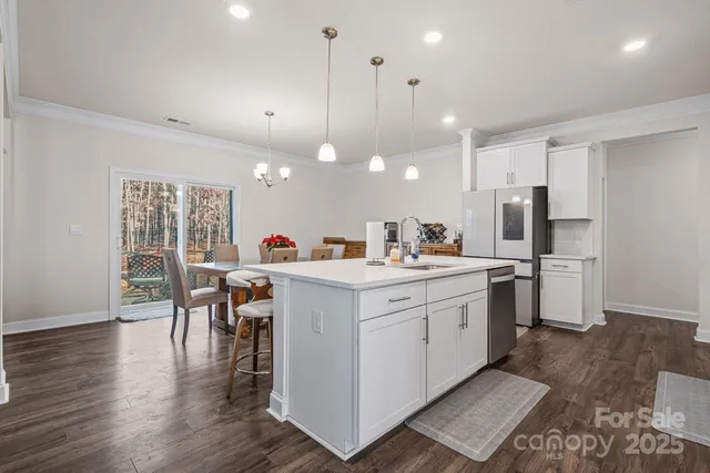 a kitchen that has a lot of cabinets a sink dishwasher and a dining table with wooden floor