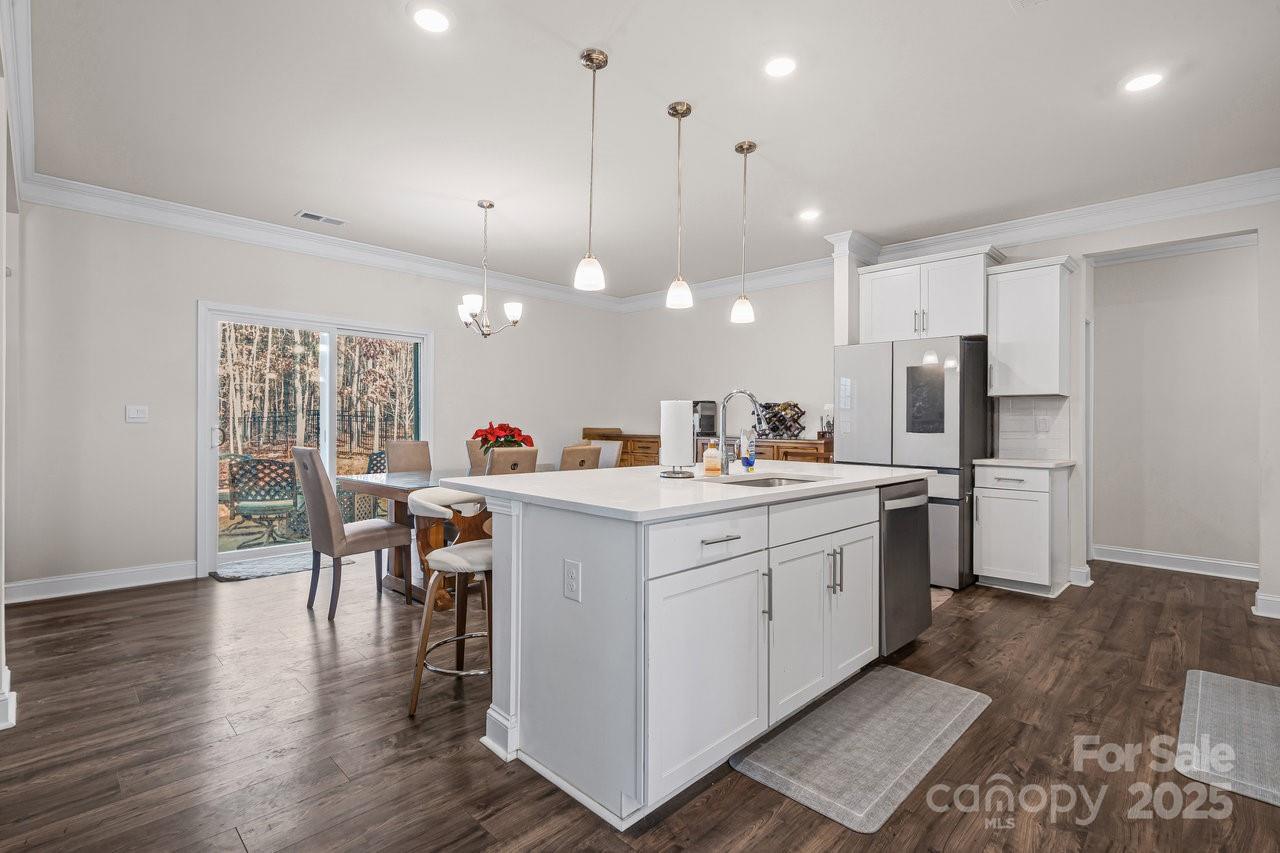 313 Streamwood Road Troutman, NC 28166 - Photo 13 of 48 a kitchen that has a lot of cabinets a sink dishwasher and a dining table with wooden floor