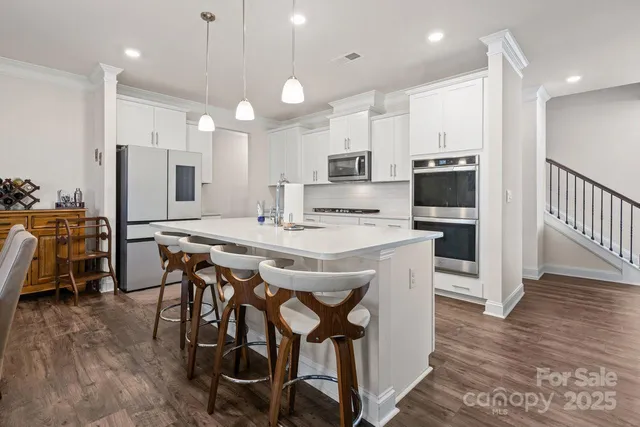 a kitchen with stainless steel appliances kitchen island granite countertop a table chairs sink and cabinets