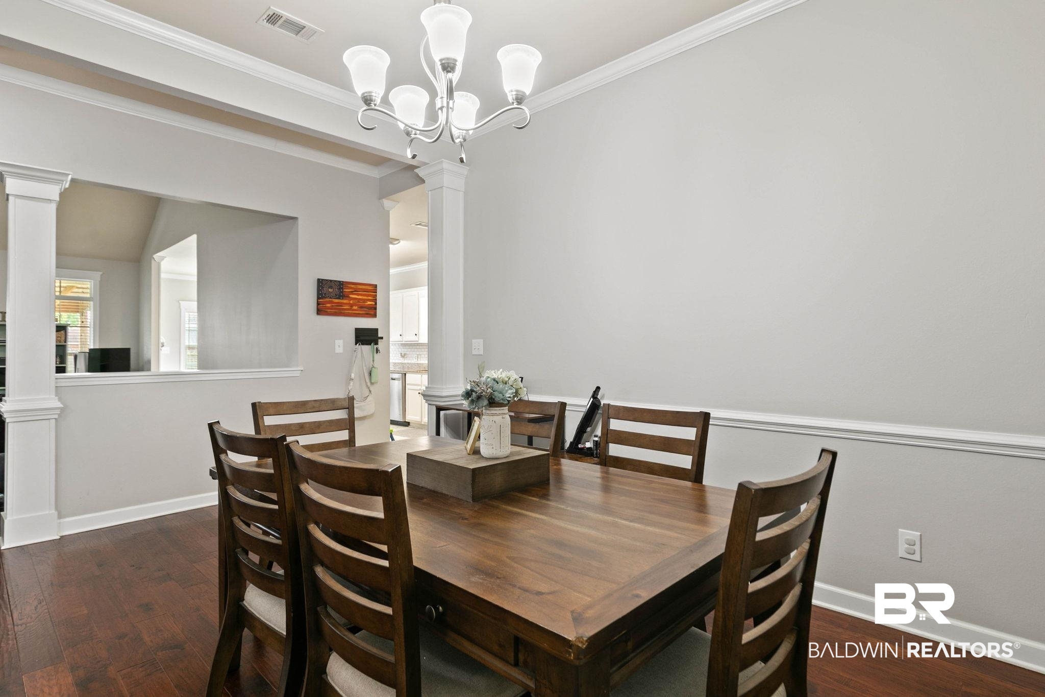 9177 Labrador Trail Theodore, AL 36582 - Photo 4 of 24 Dining area with ornate columns, dark wood-type flooring, ornamental molding, and a chandelier