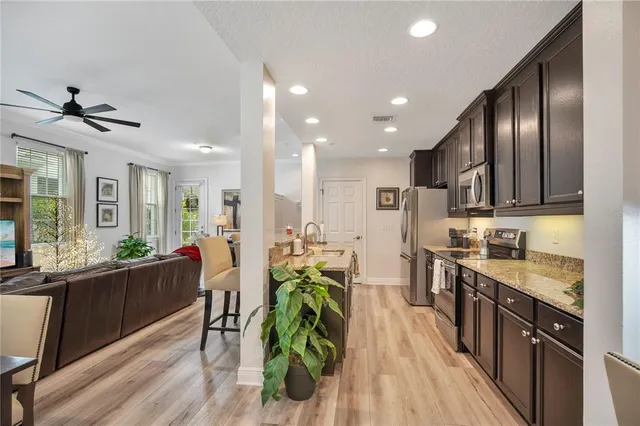 a kitchen with stainless steel appliances granite countertop a table chairs and a refrigerator