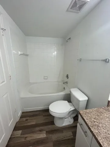 a bathroom with a granite countertop toilet a sink and bathtub