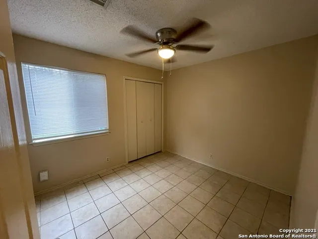 an empty room with windows and fan