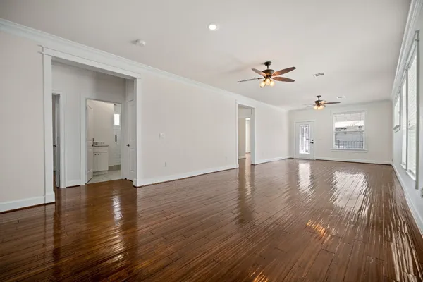 an empty room with wooden floor chandelier fan and windows