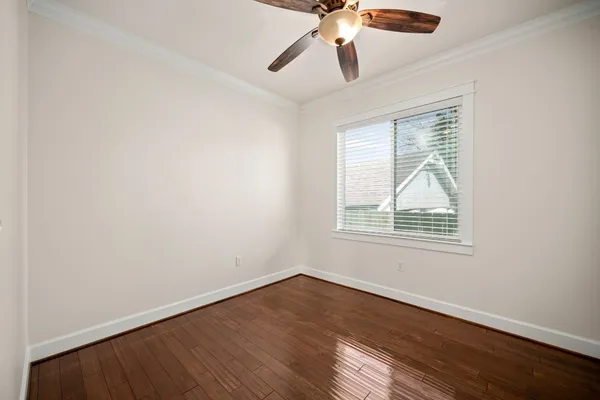 an empty room with wooden floor chandelier fan and windows