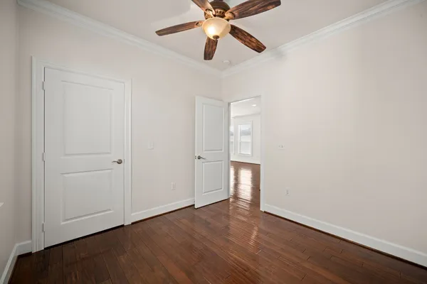 an empty room with wooden floor ceiling fan and windows