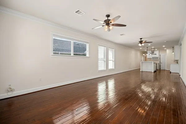a view of an empty room with wooden floor and a window