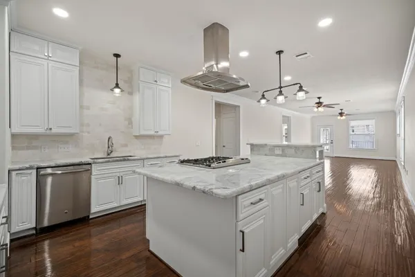 a kitchen with kitchen island granite countertop a sink cabinets and wooden floor