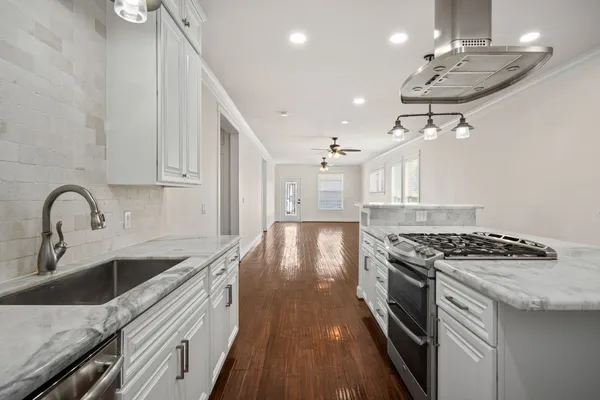 a kitchen with granite countertop a stove a sink a refrigerator and a stove