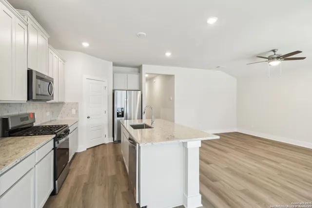 a kitchen with granite countertop a sink stainless steel appliances and cabinets