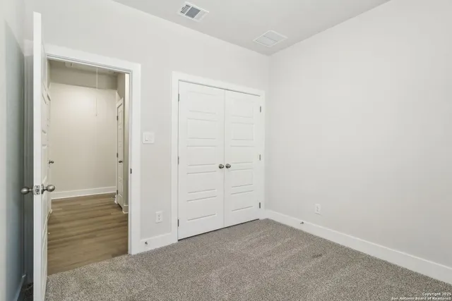 an empty room with wooden floor ceiling fan and windows