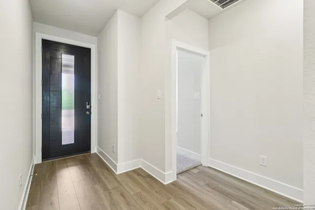 an empty room with wooden floor and entrance